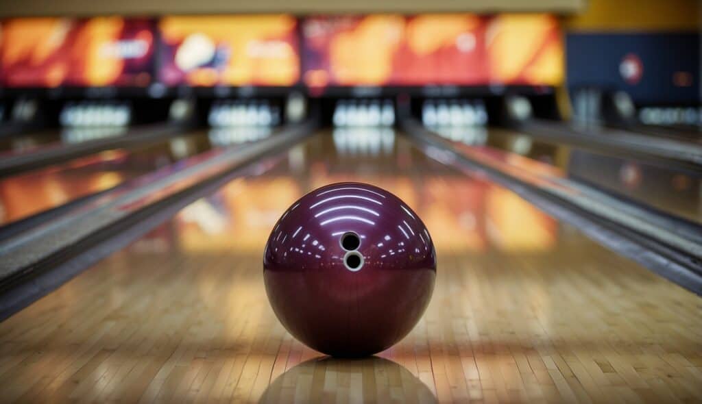 A bowling ball rolls down a polished lane, knocking over pins in a brightly lit bowling alley